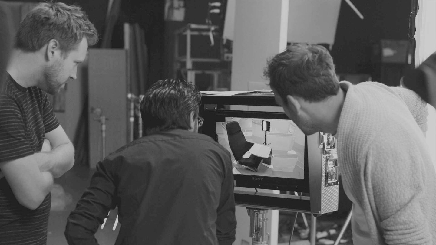 Three people looking at a screen during a film shoot