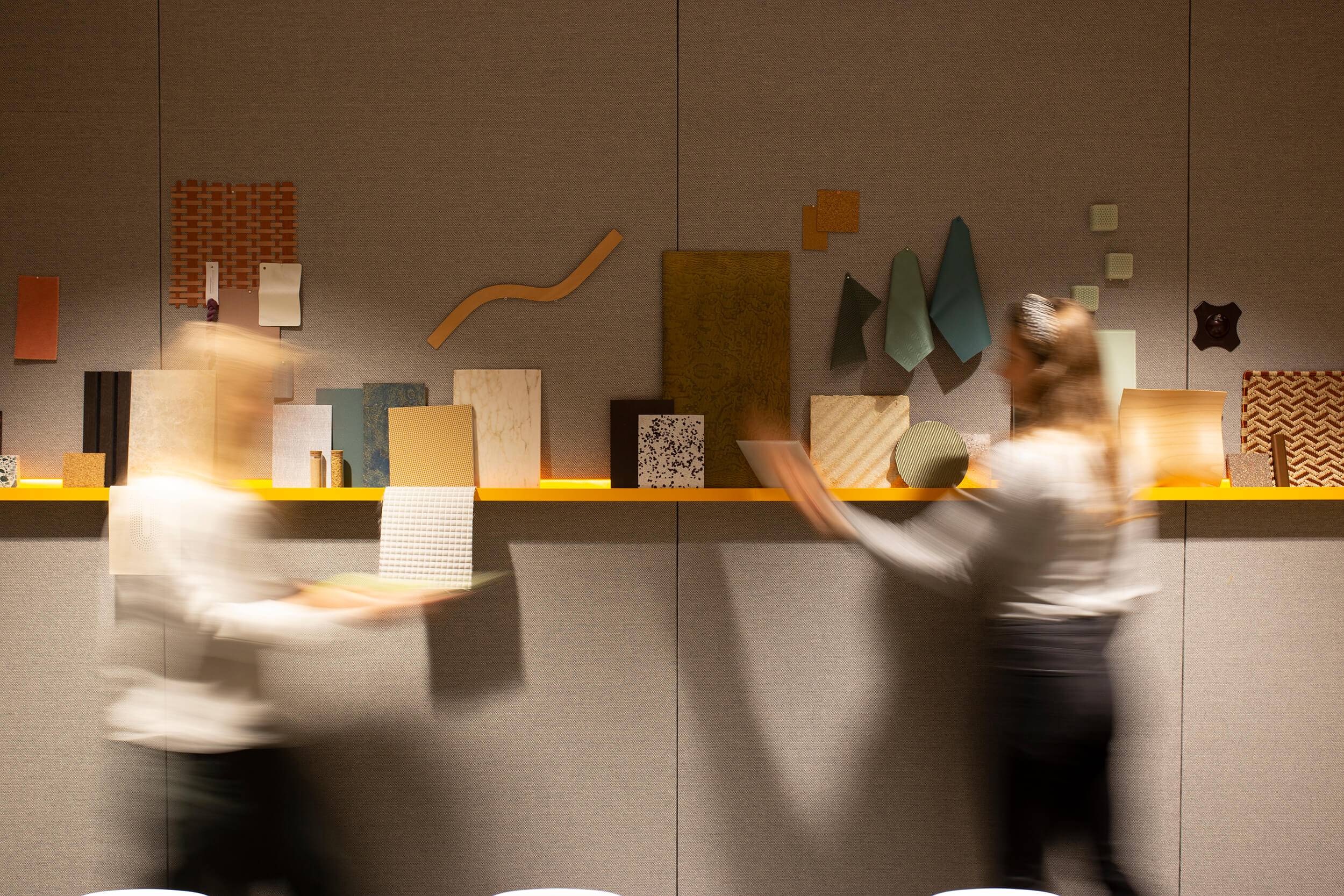 Two people putting material samples on a shelf