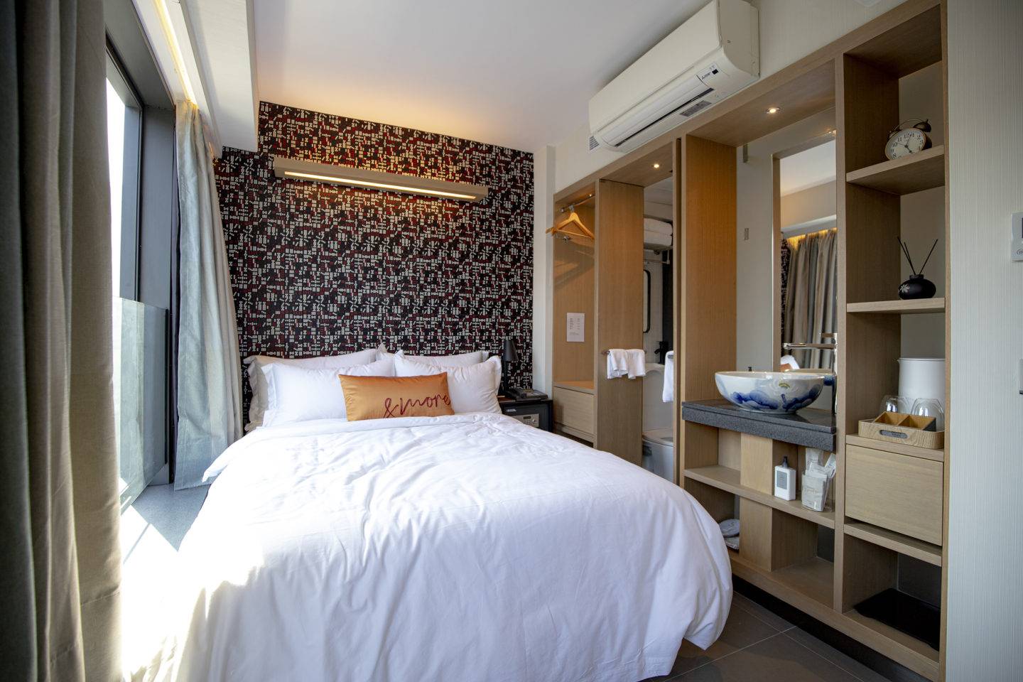 Bedroom with patterned wall and a walled storage unit with open shelving and a sink