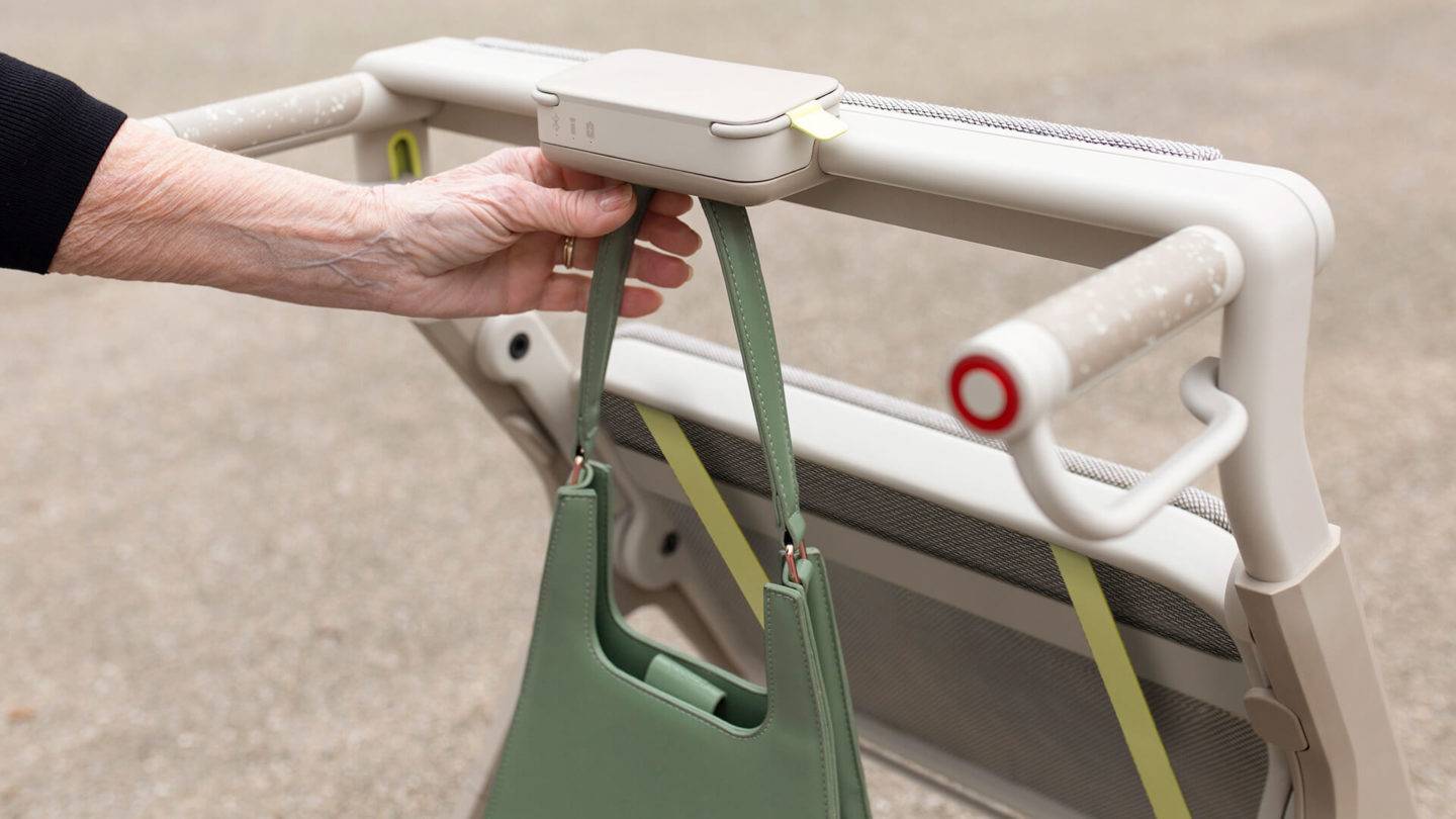 The hook below the centre of the WALKABLE frame with the model attaching a handbag