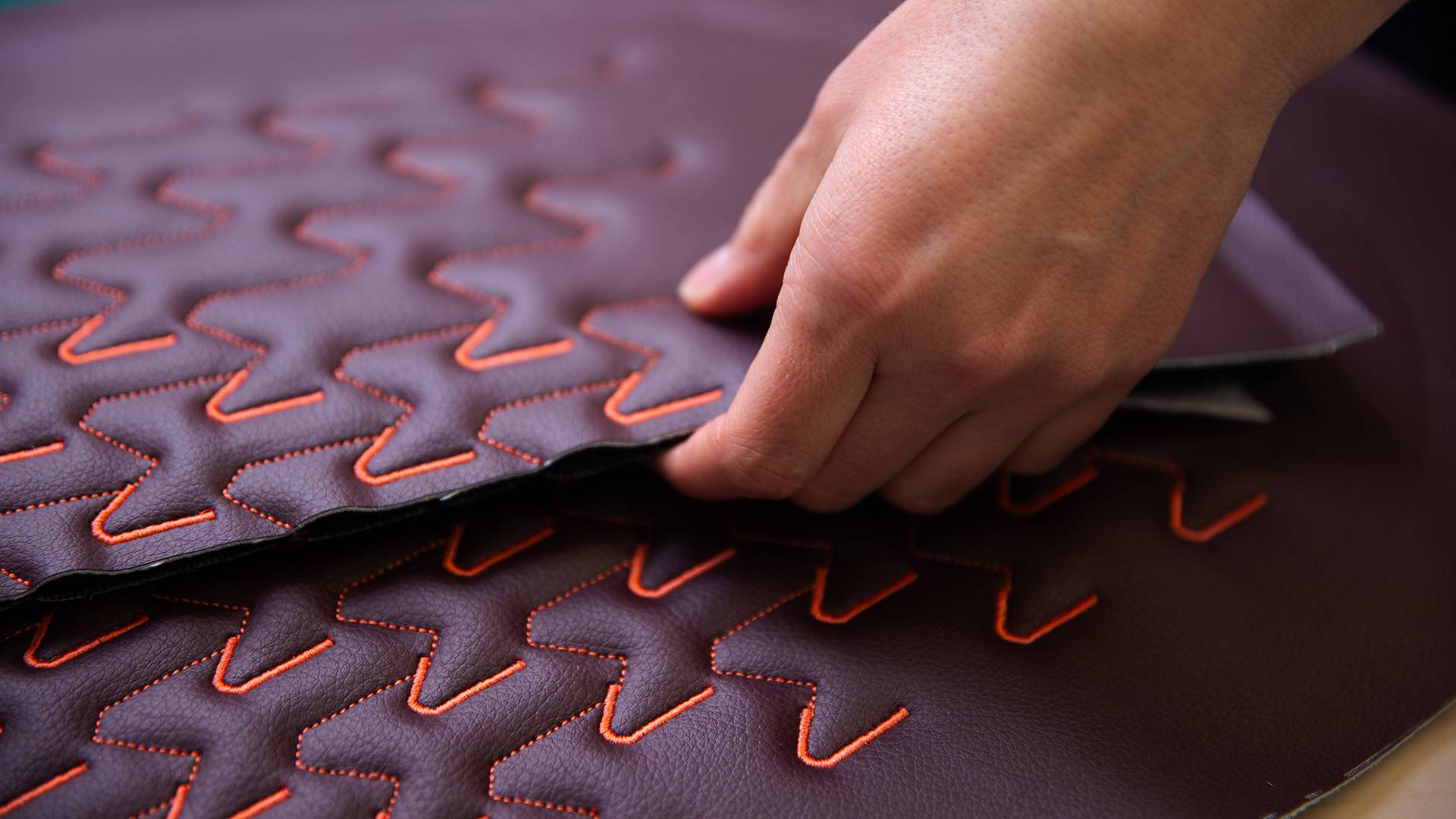 Burgandy Gen Phoenix material sample of Essence Nappa with orange pattern stitching