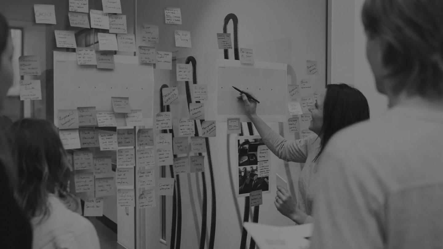 Person drawing on whiteboard with onlookers