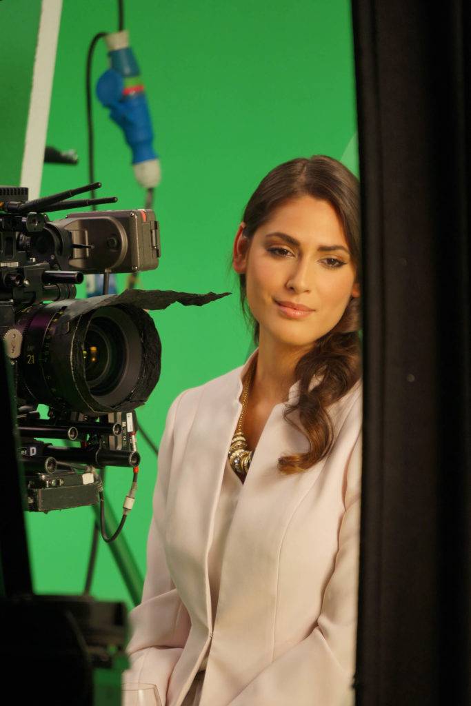 Woman at a film shoot in front of a camera with a green screen background